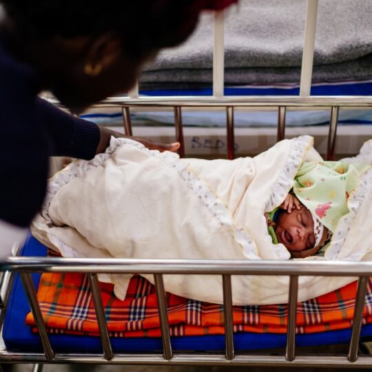 Uganda: Eine Frau beugt sich über ein Neugeborenes in einer Wiege. Ärzte der Welt leistet lebenswichtige Hilfe bei Geburten.