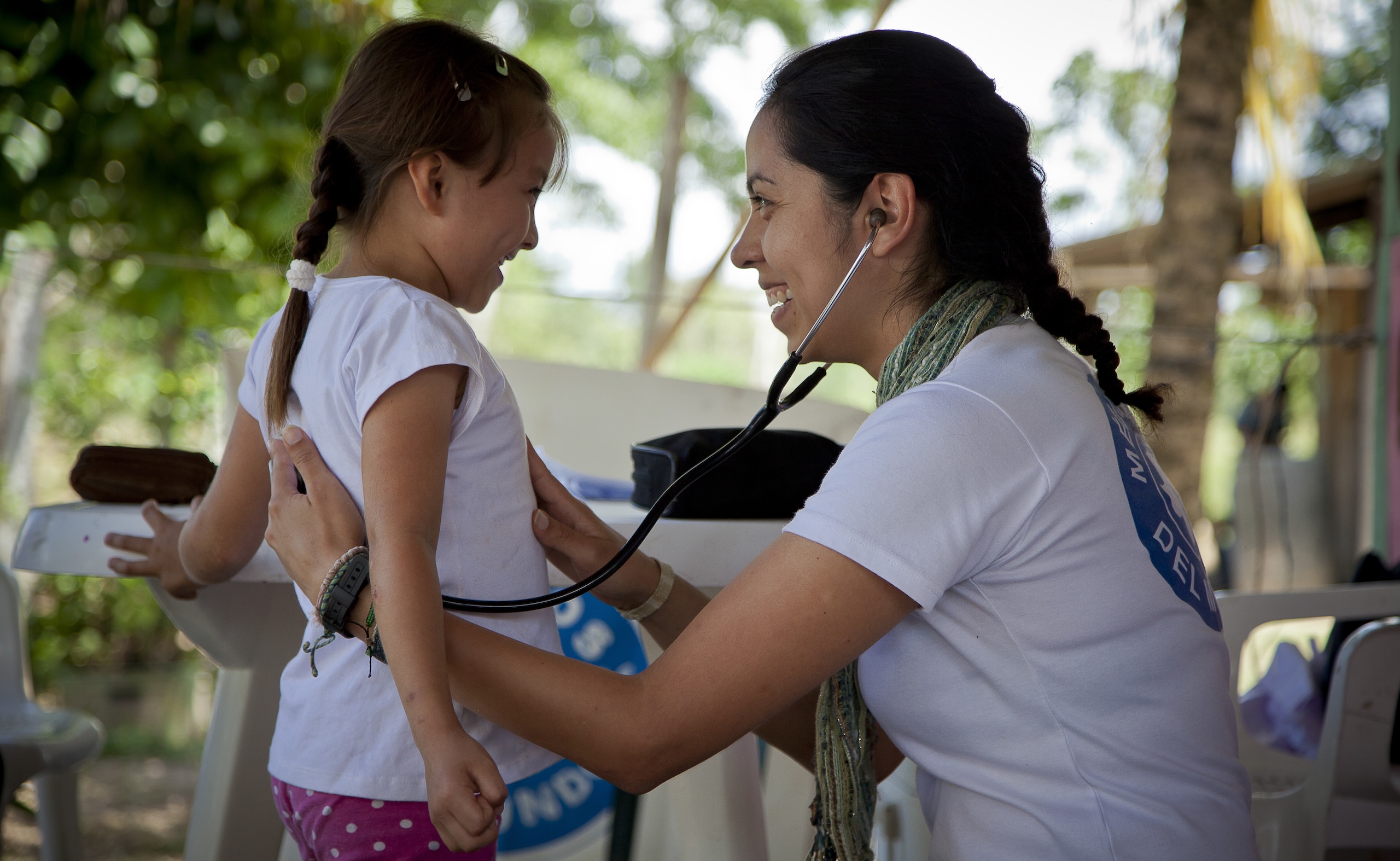 Ärzte der Welt Mitarbeitende hört ein Kind mit dem Stethoskop ab.