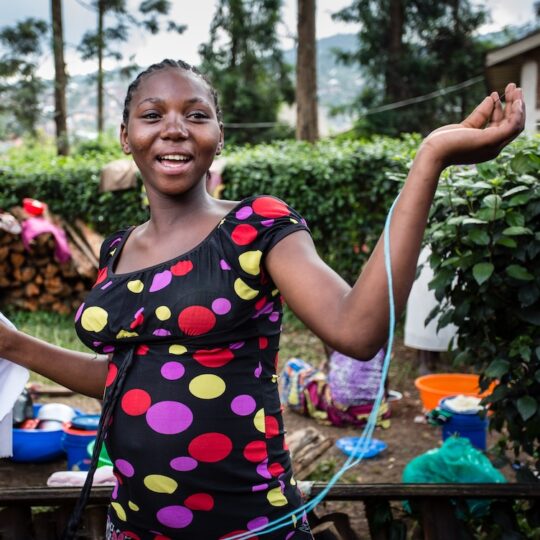 Demokratische Republik Kongo: Eine schwangere Frau mit ausgebreiteten Armen, lächelnd. Ärzte der Welt lebenswichtige Hilfe bei Geburten in der Demokratischen Republik Kongo.
