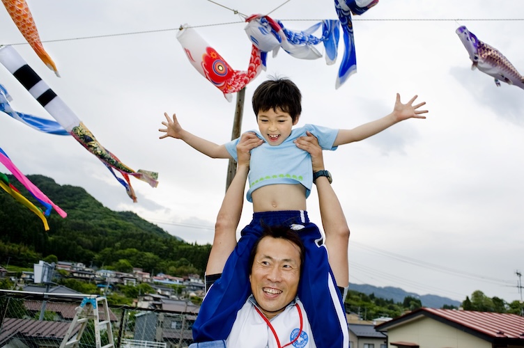 Japan: Ein Kind sitzt mit ausgebreiteten Armen auf den Schultern eines Mannes. Ärzte der Welt leistet medizinische Hilfe in Japan.