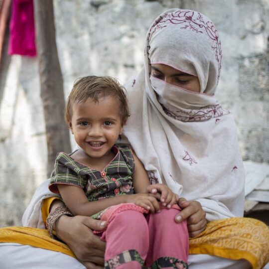 Pakistan: Eine Frau mit einem kleinen Kind auf ihrem Schoß. Ärzte der Welt leistet medizinische Hilfe in Pakistan.