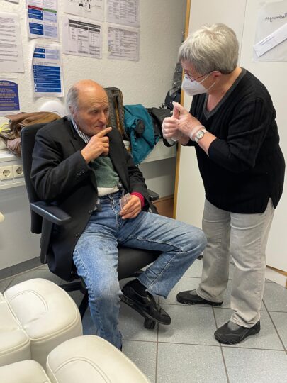 Eine Mitarbeiterin in Stuttgart, Deutschland, spricht mit einem Patienten, der auf einem Stuhl sitzt und eine Medikamentenpackung in der Hand hält. © Ärzte der Welt