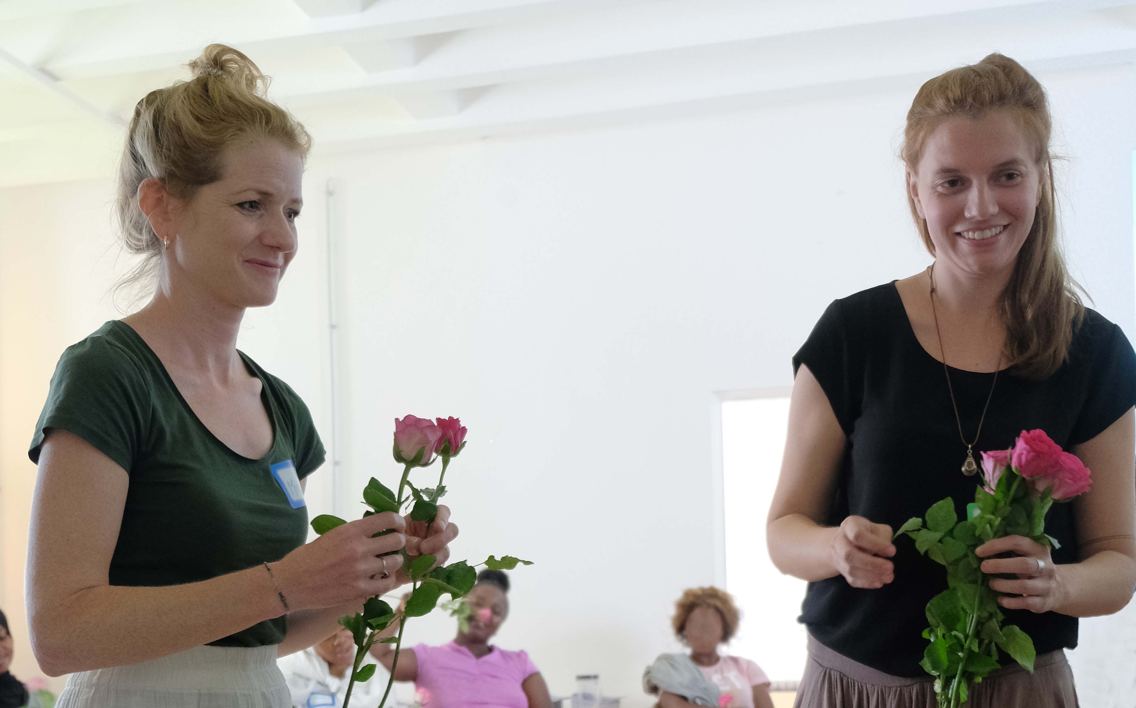Michelle Kerndl-Özcan und Lea Dannert überreichen Rosen an die Teilnehmerinnen des reach.out-Workshops. Foto: Ärzte der Welt