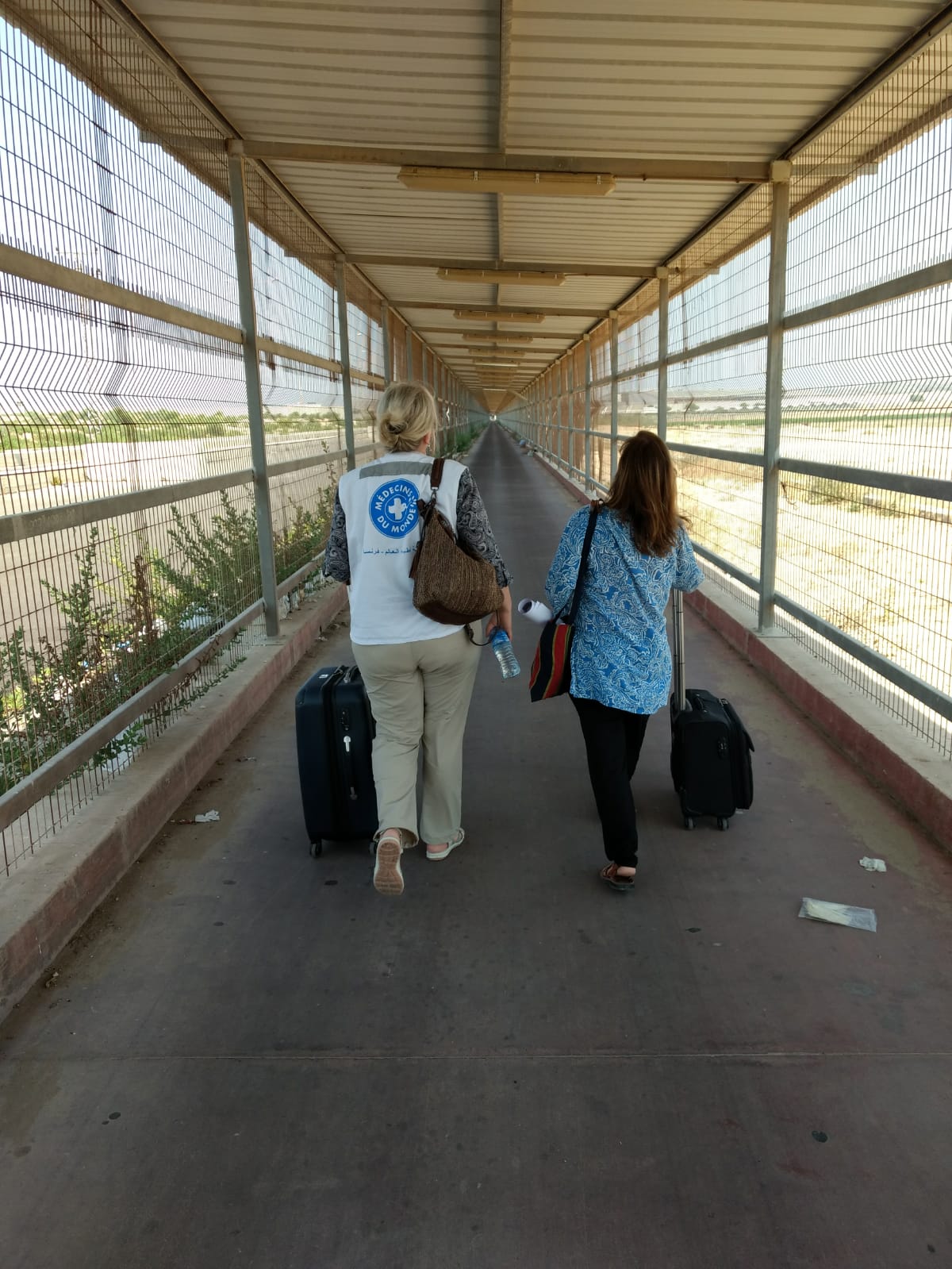 Ärzte der Welt Mitarbeiterinnen gehen durch einen 800 Meter langen, käfigartigen Gang. Die Einreise in den Gazastreifen steht unter strengsten Bedingungen - Pässe werden an beiden Enden des Korridors kontrolliert.