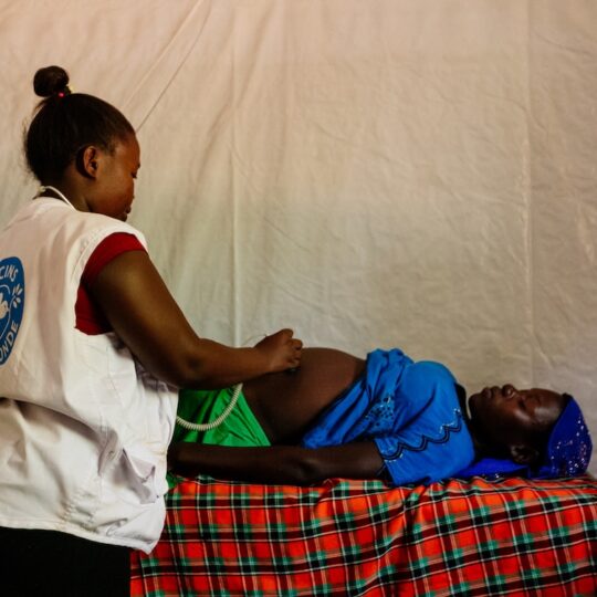 Eine schwangere Frau aus Uganda wird von einer Mitarbeiterin von Ärzte der Welt untersucht.