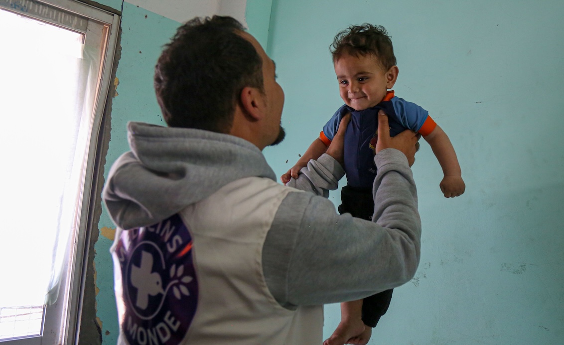 Gaza: Ein Mitarbeiter von Ärzte der Welt hebt ein lachendes Kind hoch. Ärzte der Welt leistet medizinische Nothilfe im Gazakrieg.