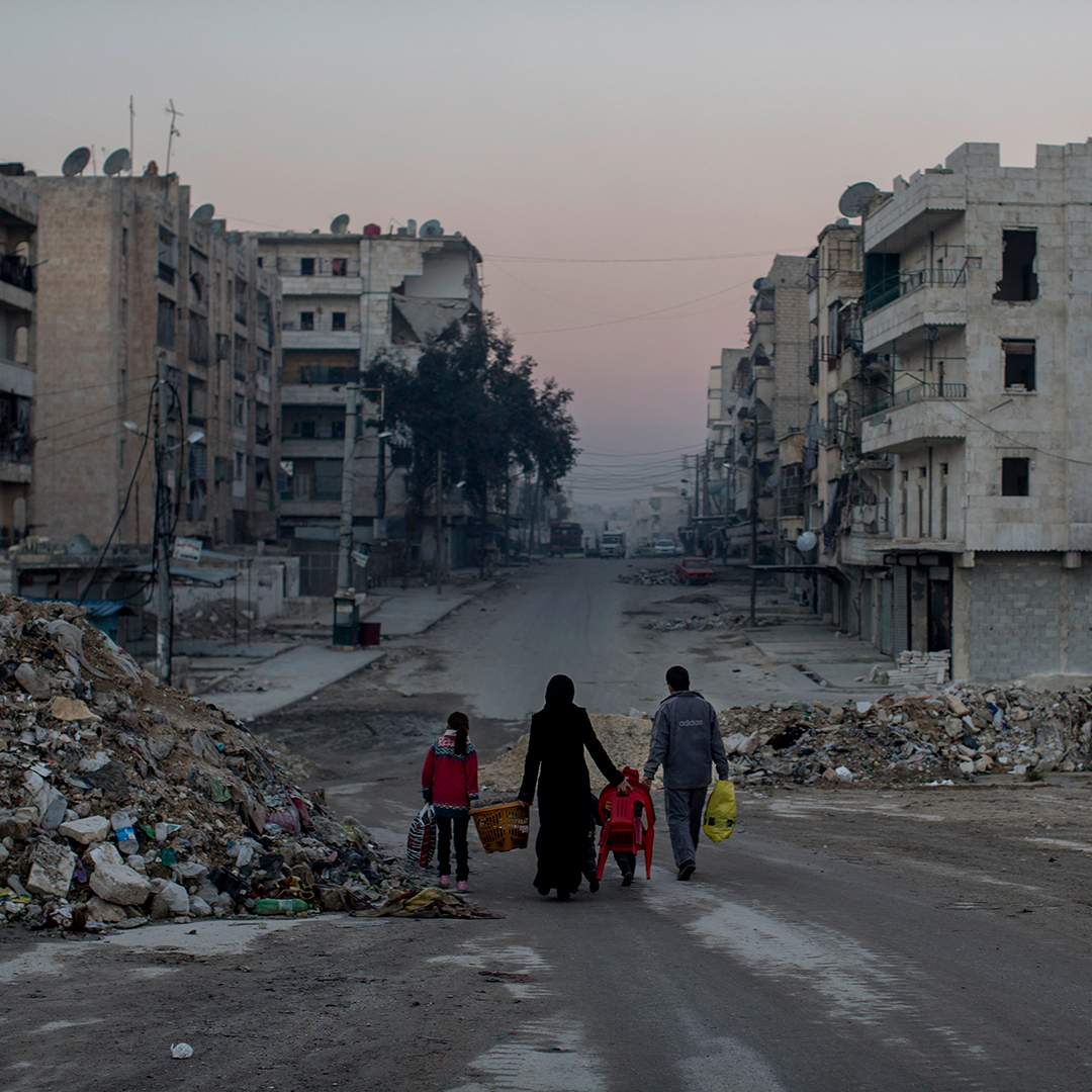 Eine syrische Familie läuft durch eine zerbombte Nachbarschaft.