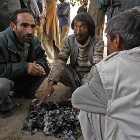 Afghanistan: Ein Mitarbeiter von Ärzte der Welt spricht mit zwei Männern, die sich die Hände an einem Feuer wärmen. © Gilbert Poitiers