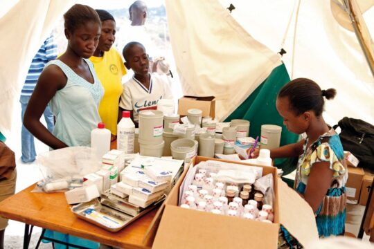 Haiti: Eine medizinische Angestellte bedient Patient*innen in einer mobilen Klinik von Ärzte der Welt. Vor ihr liegen Medikamente und medizinische Ausrüstung auf dem Tisch. © Lahcene Abib