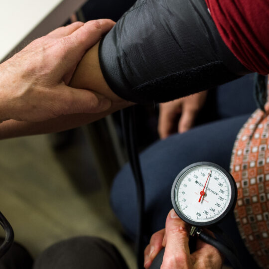 Ein Ehrenamtlicher misst einer Patientin den Blutdruck in der open.med Praxis in Hamburg. © Ärzte der Welt