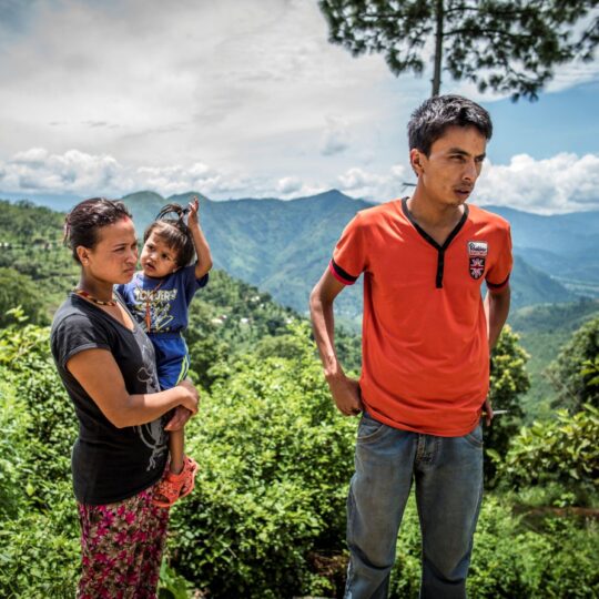 Nepal: Ein Mann steht neben einer Frau und einem Kind und schaut in die Ferne. © Olivier Papegnies