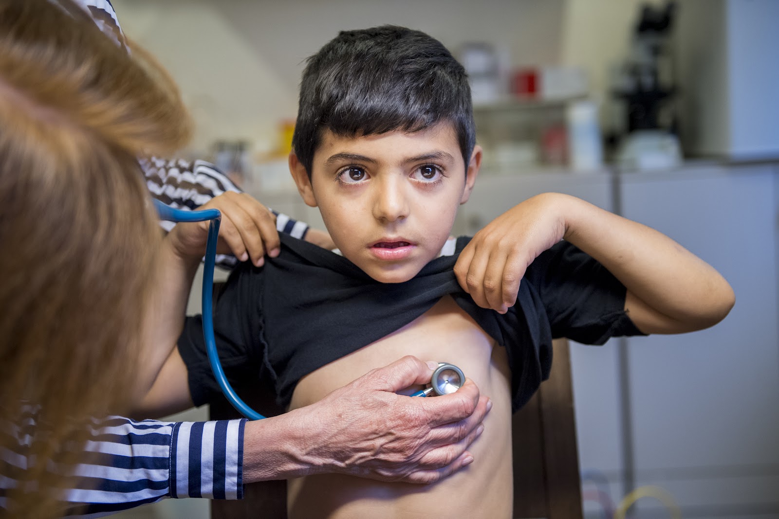 In der Hamburger Praxis untersucht eine Ärztin einen Jungen mit einem Stethoskop. © Bente Stachowske