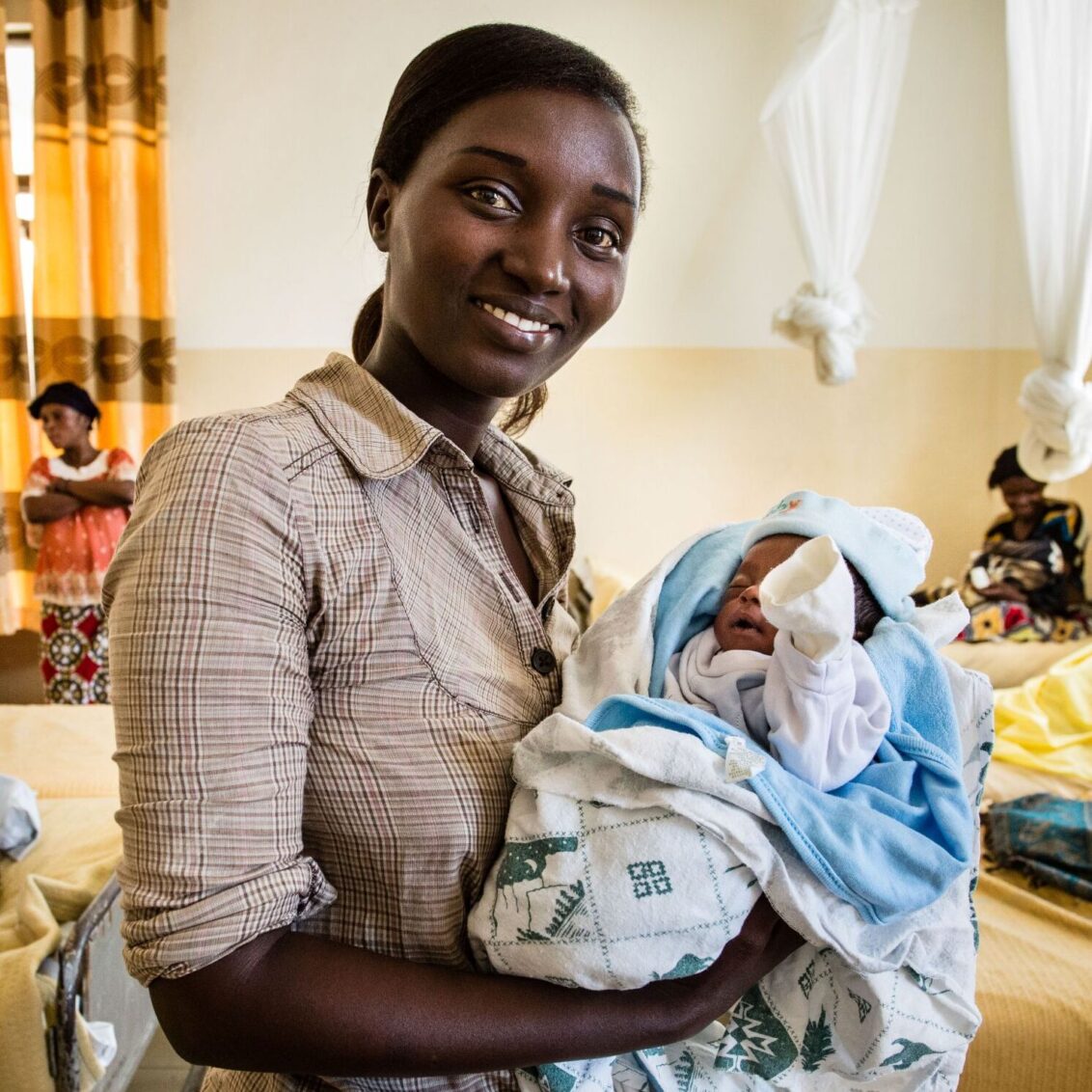 Kongo: Eine frau hält ein Baby auf dem Arm und lächelt in die Kamera. © Kristof Vadino