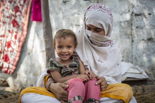 Pakistan: Ein Kleinkind sitzt auf dem Schoß einer Frau, lächelnd. In Pakistan leistet Ärzte der Welt medizinische Hilfe, unter anderem auch für Mütter und Kinder. © Saiyan Bashir