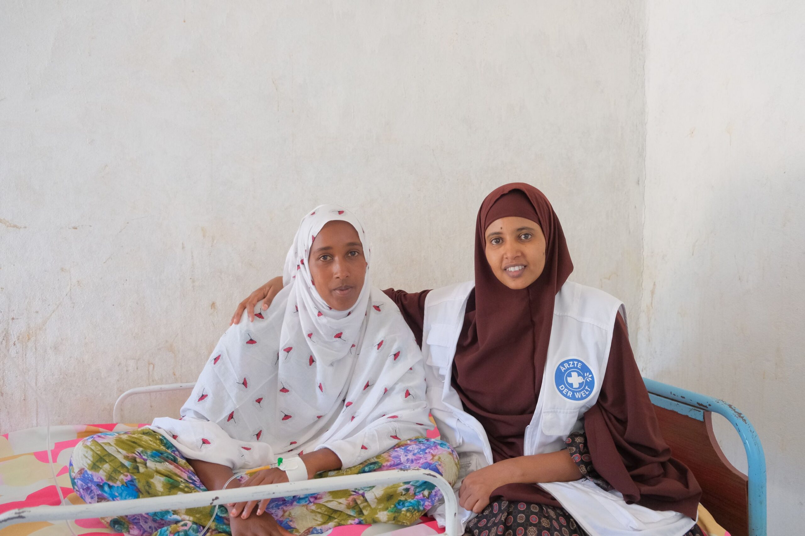 Äthiopien: Eine Mitarbeiterin von Ärzte der Welt sitzt neben einer Patientin auf einer Krankenliege und hat den Arm um sie gelegt. © Ärzte der Welt