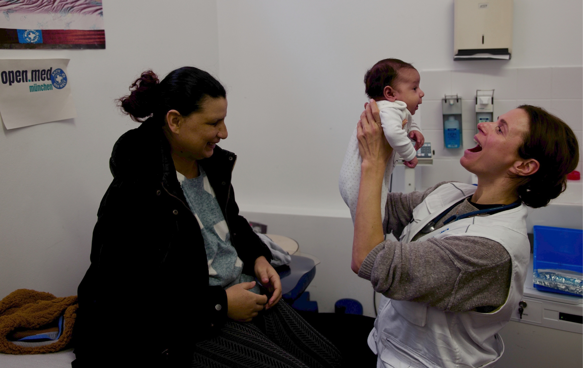 Eine Ehrenamtliche hält ein Baby hoch. Ärzte der Welt leistet medizinische Hilfe in der open.med-Praxis in München. © Ärzte der Welt