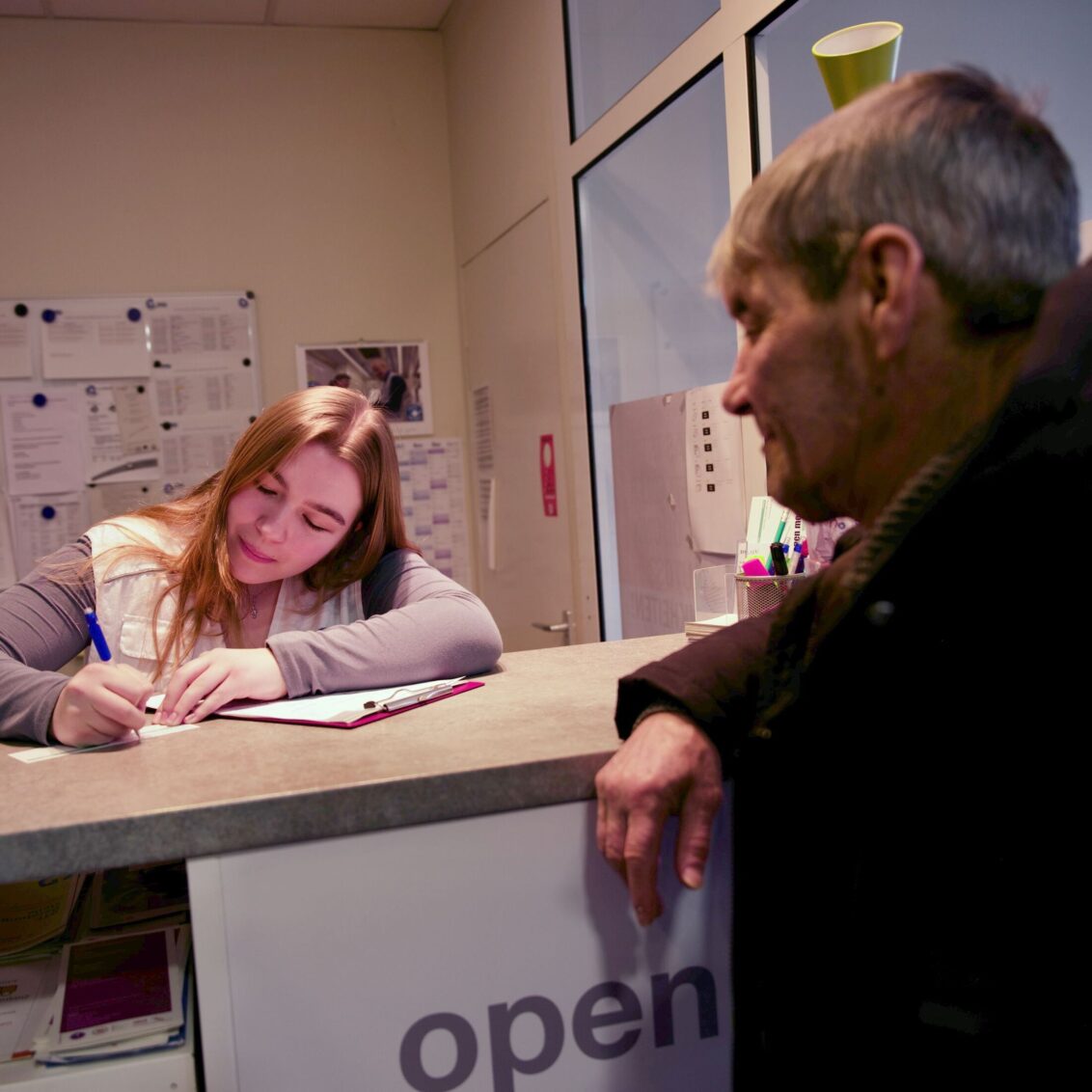 Deutschland: Ein Mann steht an der Rezeption einer open.med Praxis in München. © Till Mayer