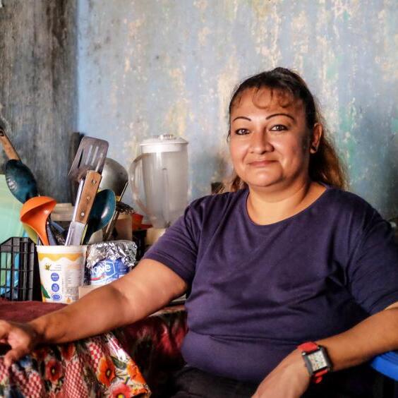 Mexiko: Glenda Hernández sitzt an einem Küchentisch und lächelt in die Kamera. © Nadja Massun