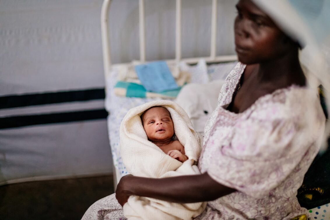 Uganda: Eine Frau sitzt auf einer Pritsche, mit einem Baby in ihrem Arm. Ärzte der Welt leistet lebenswichtige Hilfe bei Geburten. © Sébastien Duijndam