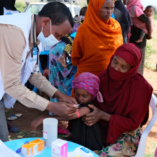 Ein Mitarbeiter von Ärzte der Welt misst einem Mädchen mit einem Maßband den Armumfang. © Ärzte der Welt