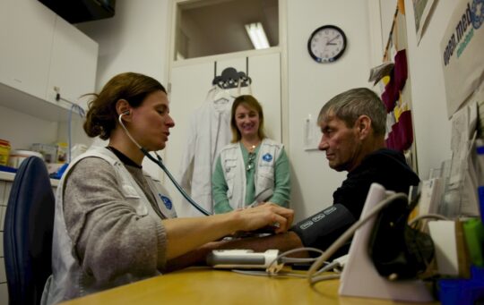 Open.med-Sprechstunde in München: Eine Ärztin misst den Blutdruck eines Patienten. Ärzte der Welt bietet kostenlose Sprechstunden in Deutschland an. © Till Mayer