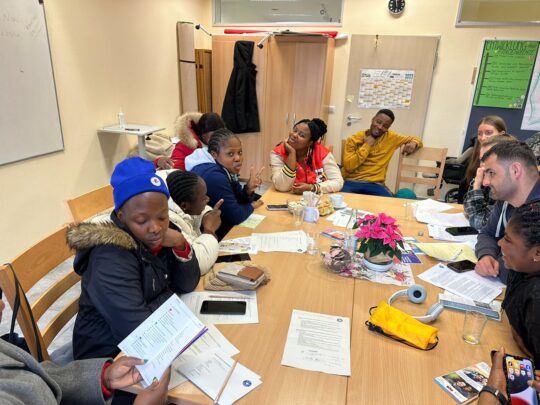 Mehrere Frauen und Männer sitzen um einen Tisch und unterhalten sich. © Ärzte der Welt