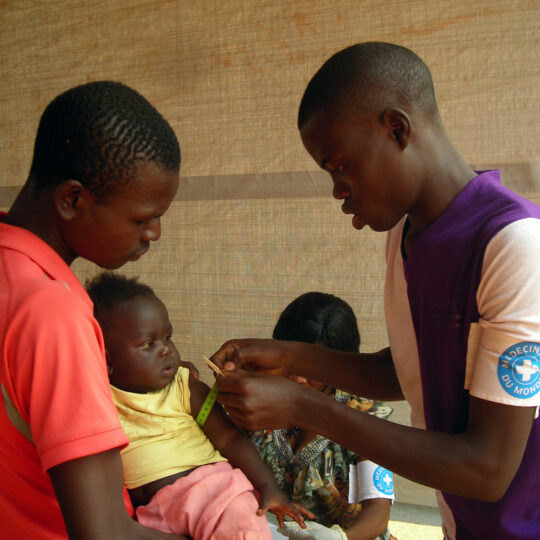 Zentralafrikanische Republik: Ein Kind auf dem Arm eines Mannes wird von Mitarbeitenden von Ärzte der Welt auf Unterernährung untersucht. © Jacky Perrudin