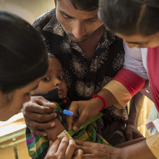 Bangladesch: Ein Kind in den Armen seines Vaters wird auf Mangelernährung untersucht. © A. Finistre