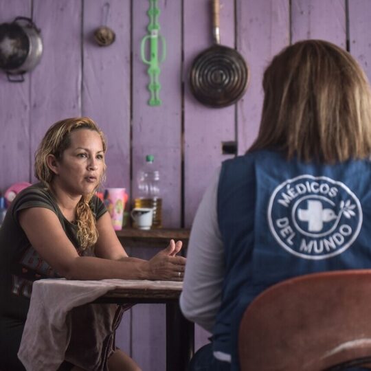 Eine Mitarbeiterin und eine Kolumbianerin sitzen an einem Tisch und unterhalten sich. © Quentin Top