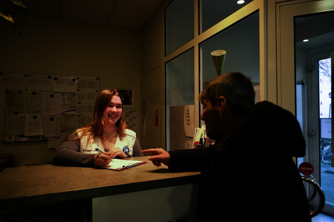 © Til Mayer München: Ein Mann und eine Mitarbeiterin von Ärzte der Welt stehen sich am Empfangstresen von open.med gegenüber. © Til Mayer