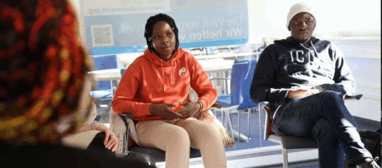 3 Personen befinden sich im Dialog. Die Frau in der Mitte erzählt etwas.