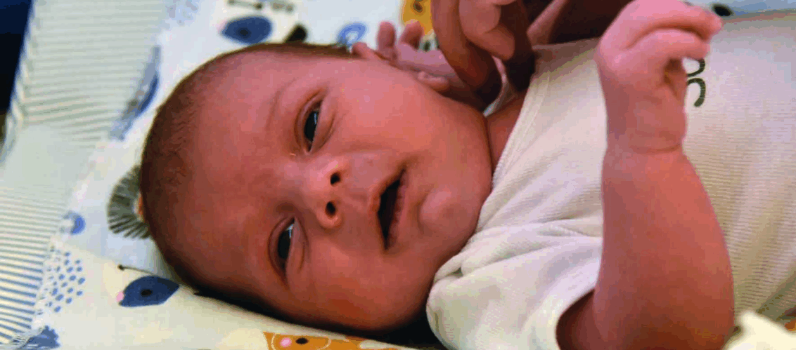 ©ChrisSchmid Ein Säugling liegt in der Krippe und schaut direkt in die Kamera