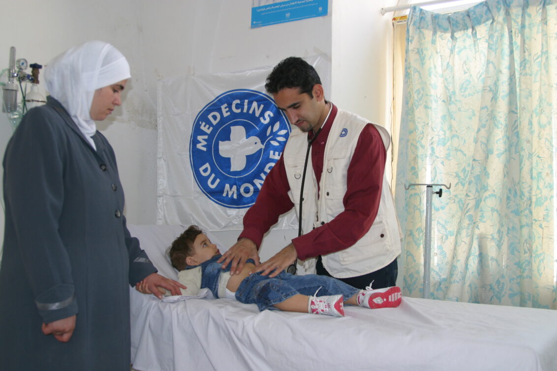 Ein Mitarbeiter von Ärzte der Welt untersucht einen Jungen.