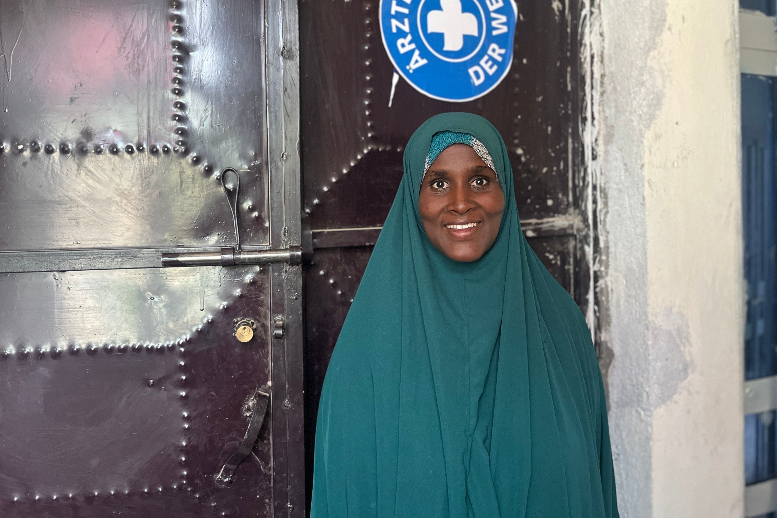 Eine Patientin posiert lächelnd vor der Kamera vor dem Eingang der Räumlichkeiten von Ärzte der Welt in der Region Somali in Äthiopien. © Ärzte der Welt