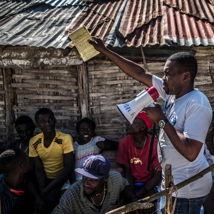 In Haiti nutzt ein Mitarbeiter von „Ärzte der Welt“ ein Megafon, um den Dorfbewohner*innen gesundheitsbezogene Informationen zu vermitteln. © Olivier Papegnies